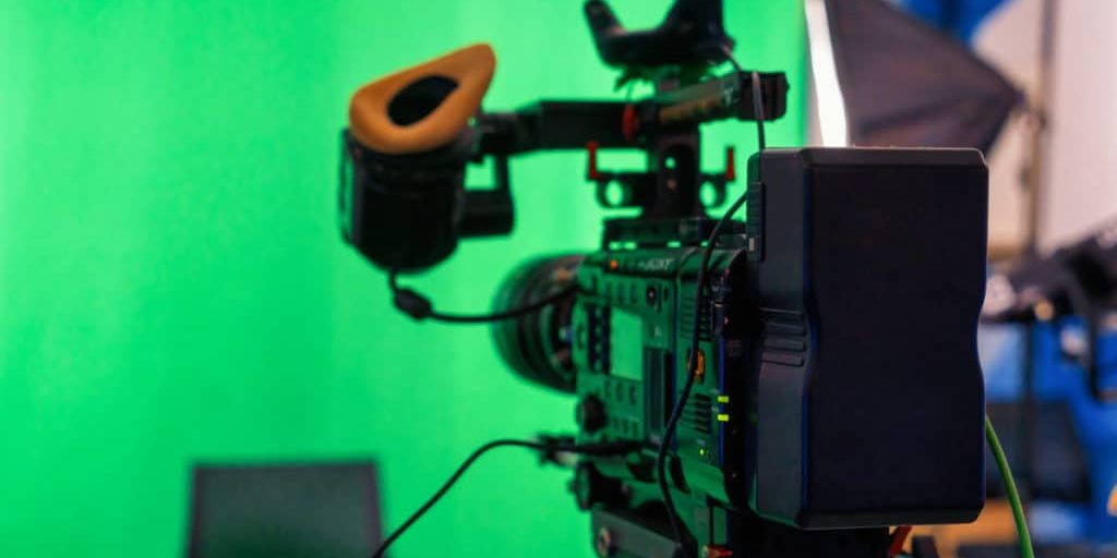 Green screen backdrop with professional video camera in foreground